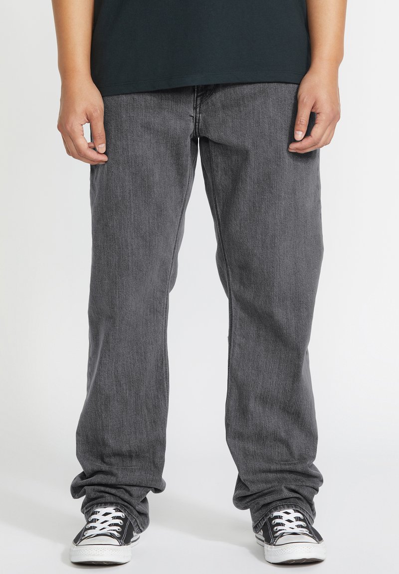 Vaqueros de mezclilla gris con un diseño de pierna recta, que presentan una textura sutil y costuras en contraste, combinados con zapatillas negras de corte bajo.