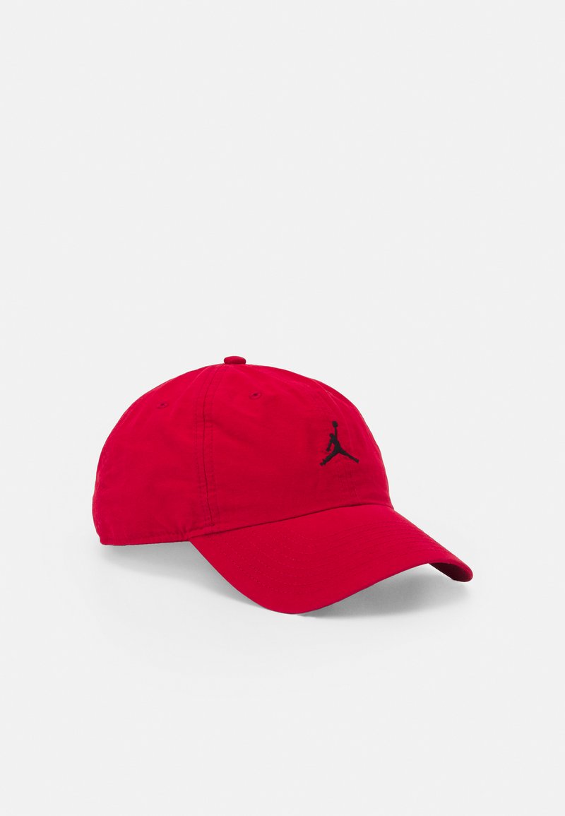 Casquette de baseball rouge avec une visière courbée et un logo en silhouette noir d'un joueur de basket-ball sautant, placée sur un fond blanc.