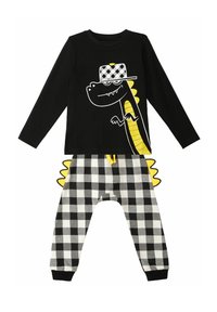 Schwarzes Longsleeve-Oberteil mit einem Cartoon-Drachenmotiv und gelben Akzenten, kombiniert mit schwarz-weißen karierten Jogginghosen.