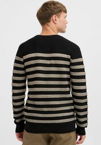 Black sweater with horizontal beige stripes, ribbed cuffs and hem. Fitted design with a crew neck, made from a textured knitted material.