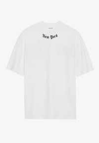 Camiseta de algodón blanca con cuello redondo y mangas cortas, con texto negro "New York" impreso en la parte superior del pecho.