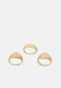 Anéis de ouro com um design liso e arredondado. Três anéis têm alturas e larguras variadas, apresentando superfícies polidas e formas minimalistas.