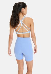 Ljusblå atletisk sport-bh med korsade ryggband, kombinerad med matchande högmidjade shorts. Slät, elastisk tyg.