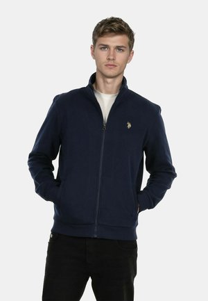 Navy zip-up jacket in a smooth, textured fabric, featuring a high collar and an embroidered logo on the left chest.