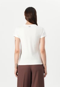 Weißes Baumwoll-T-Shirt mit kurzen, umgeschlagenen Ärmeln, rundem Ausschnitt und einem kleinen "HUGO"-Logo, das hinten in der Nähe des Ausschnitts aufgedruckt ist.