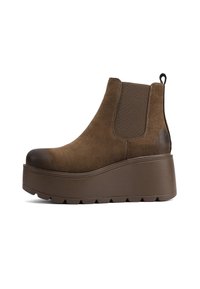 Stivale alla caviglia in suede marrone con suola a piattaforma rialzata, pannelli laterali elasticizzati e un'ansietta sul retro per una facile calzata. Dettaglio del puntale liscio.