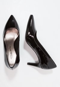 Schwarze Lackleder-High Heels mit spitzem Zehenbereich und schmalem Absatz. Verfügt über ein ausgeschnittenes Seitendesign und eine metallische Innensohle.
