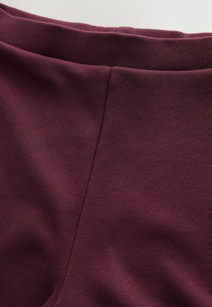 Bordo audinys, struktūruota paviršiaus tekstūra, su lygiu juosmens diržu. Šoninėse siūlėse matomas detalus siuvimas, suteikiantis pritaikytą išvaizdą.