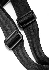 Dos correas ajustables de nailon negro con hebillas rectangulares de plástico sobre un fondo blanco.