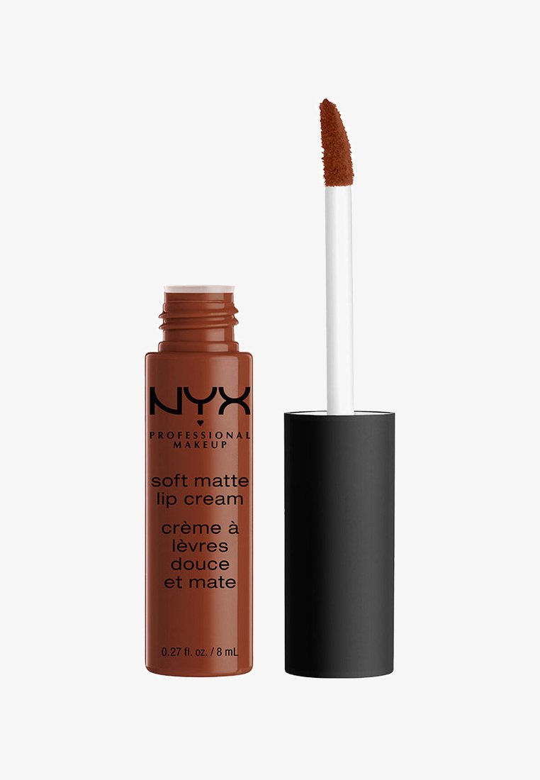 NYX Soft Matte Lip Cream w cylindrycznej, błyszczącej brązowej tubce z czarnym tekstem. Dołączony jest biały aplikator z miękką końcówką.