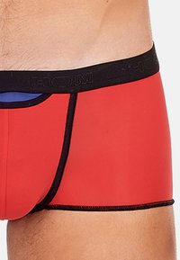 Red boxer shorts with a black waistband featuring the brand name "HOM." They have a smooth texture and fitted design.