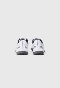 Pantofi sport albi, cu un design elegant, talpă din cauciuc, accente texturate și un detaliu de logo negru pe călcâi. Compacți și ușori.