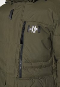 Olivově zelená zateplená bunda sezipem, polstrovaná textura, boční kapsy a reflexní logo na hrudi. Černé zipové detaily.