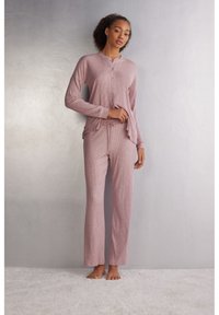 Ljusrosa ribbad pyjamas-set med en knäppning henley-topp och byxor med dragsko och avslappnad passform. Mjuk textur och långa ärmar.