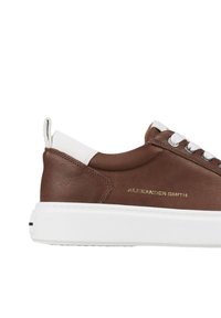 Sneaker in pelle marrone con dettagli bianchi, punta rotonda, occhielli argentati e nome del marchio impresso in oro di lato. Suola bianca spessa.