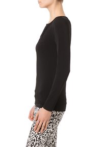 Top nero a maniche lunghe con design aderente e scollatura rotonda, abbinato a leggings bianchi e neri a fantasia con stampa animale.