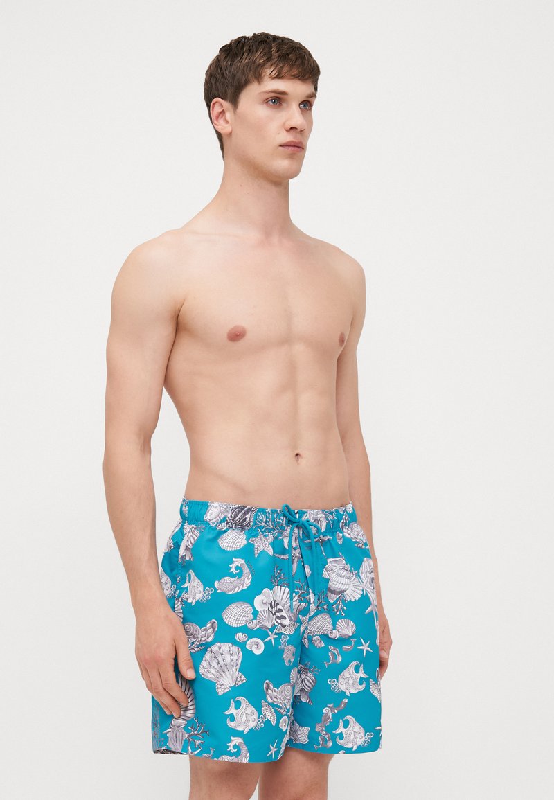 Turkise badebukser med et hvidt mønster af muslingeskaller og havliv, med elastisk talje og justerbar snor.