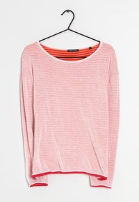 Lichtroze gestreepte blouse met lange mouwen en een rode en oranje gestreepte binnenvoering, hangend aan een zwarte hanger tegen een witte achtergrond.