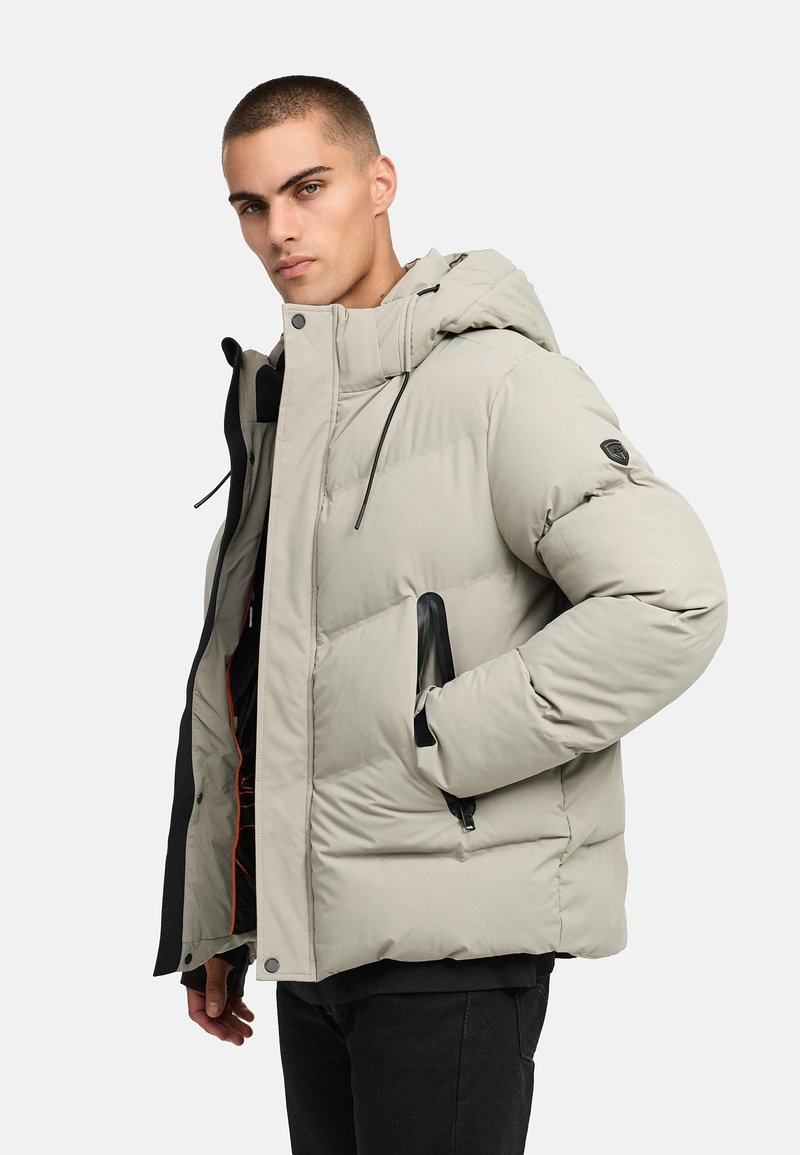 Ljusgrå pufferjacka med huva, med zippered fram, sidofickor och svarta detaljer. Slät textur och quiltat mönster.