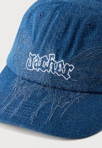 Μπλε καπέλο τζην με κεντημένο το "JACKER" σε λευκό, διαθέτοντας περίπλοκες λεπτομέρειες πεταλούδας και σχέδιο με νήμα στο ίδιο χρώμα στο μπροστινό μέρος.