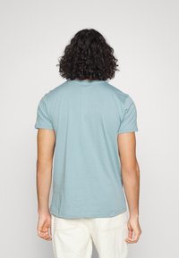 Camiseta de algodón azul claro con mangas cortas, cuello redondo y un corte relajado. Detalle de costura visible a lo largo del dobladillo.