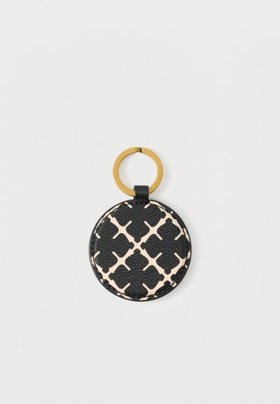 Στρογγυλό μπρελόκ από δέρμα σε μαύρο και μπεζ με σχέδιο και χρυσό μεταλλικό δαχτυλίδι σε λευκό φόντο.