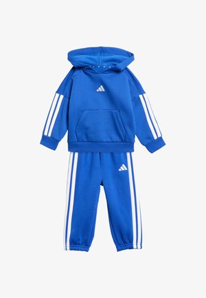 Modrý Adidas športový oblek pozostávajúci z mikiny s kapucňou a predným vreckom, bielymi pruhmi na rukávoch a zodpovedajúcich nohavíc s elastickými manžetami.