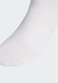 Calcetín blanco hecho de material texturizado, que presenta una mezcla de patrones acanalados y suaves. El diseño incluye un talón y una punta reforzados.