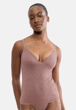 Kvinde iført en malve mønstret camisole top og matchende undertøj står mod en ensartet lys baggrund.
