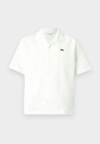 Biele košeľa s krátkym rukávom na gombíky z textúrovaného materiálu, s vyšívaným zeleným logom na ľavej hrudi a klasickým talianskym golierom.