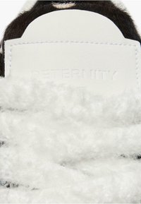 Lumivalge faux fur materjal tekstuuriga, koheva pinnaga. Musta ja valge nahkvarvas ning reljeefne "RETERNITY" logo.