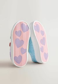 Zapatos multicolores con una suela de corazón en tonos rosa y lavanda, superficie texturizada y un acento azul brillante en el lateral.