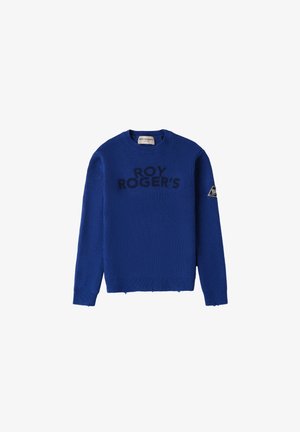 Suéter de punto azul con textura acanalada, cuello redondo y logo "ROY ROGER'S" en negro. Presenta un acento triangular en la manga izquierda.
