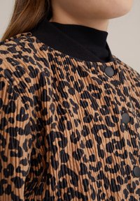 Leopardmönstrad jacka med en ribbad svart krage, texturerad tyg, plisserad design och svarta knappdetaljer.