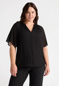 Blusa nera con maniche corte e fluttuanti, scollatura a V e texture plissettata sulle spalle. Tessuto morbido con un design fluido.