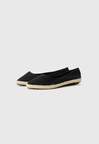 Svart kanvas espadriller med spiss tå og såle av naturlig jute-rep. Jevn tekstur, lavskåret design, og ingen synlig maskinvare eller detaljer.