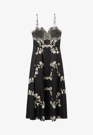 Vestido negro con tirantes delgados, que presenta un intrincado bordado floral blanco y un corpiño ajustado. Diseño de falda acampanada, de longitud hasta la mitad de la pantorrilla.