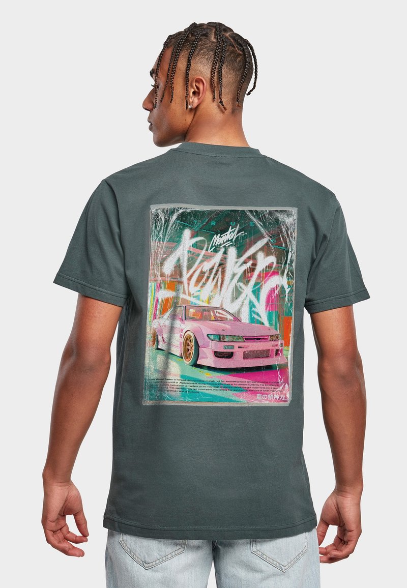 Homme aux cheveux tressés vu de dos, portant un t-shirt vert foncé avec un motif coloré représentant une voiture de sport rose et un graffiti abstrait au dos.