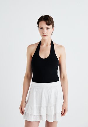 Haut halter noir avec un décolleté plongeant associé à une mini-jupe blanche à plusieurs couches, ornée de broderies florales et d'une finition texturée.