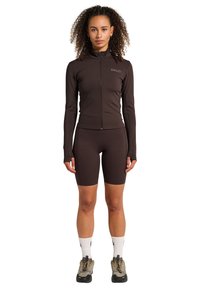 Brun formsydd träningsjacka med dragkedja, hög krage och matchande shorts. Har långa ärmar och subtil branding på bröstet.