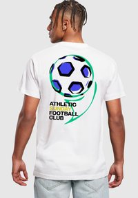 Bílý bavlněný tričko s grafikou fotbalového míče v modré a černé barvě, textem "ATHLETIC SUNDAY FOOTBALL CLUB" a zakřivenými zelenými akcenty.