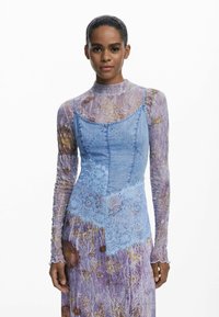 Vestido de mezclilla con un corsé ajustado, acentos de encaje y mangas largas, texturizadas y moradas con un patrón floral. Colores azul claro y morado.
