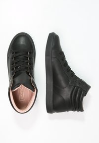 Černé vysoké tenisky s texturovanou kůží, zaoblenou špičkou a šněrováním vpředu. Světle růžová podšívka a černá gumová podrážka.