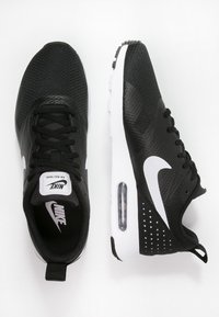 Svarta sportskor med ovandel i mesh, vit Nike-logotyp, luftkuddar, vadderad krage och mönstrad sula med perforeringar.