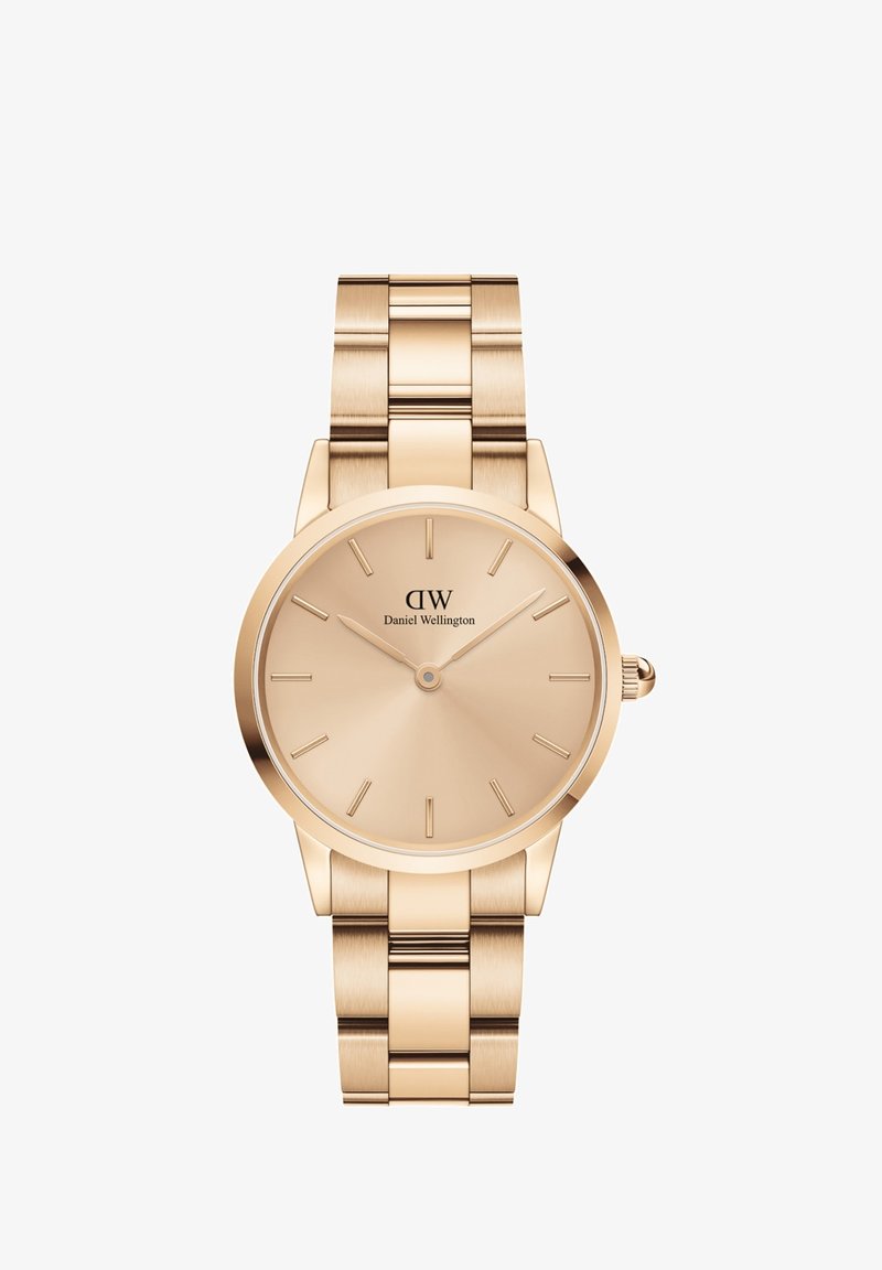 Zelta tonis analoga pulksteņa ar apaļu korpusu, minimālistisku ciparnīcu un savienotu metāla siksniņu. Atzīmes ir vienkāršas ar gludu, pulētu apdari.