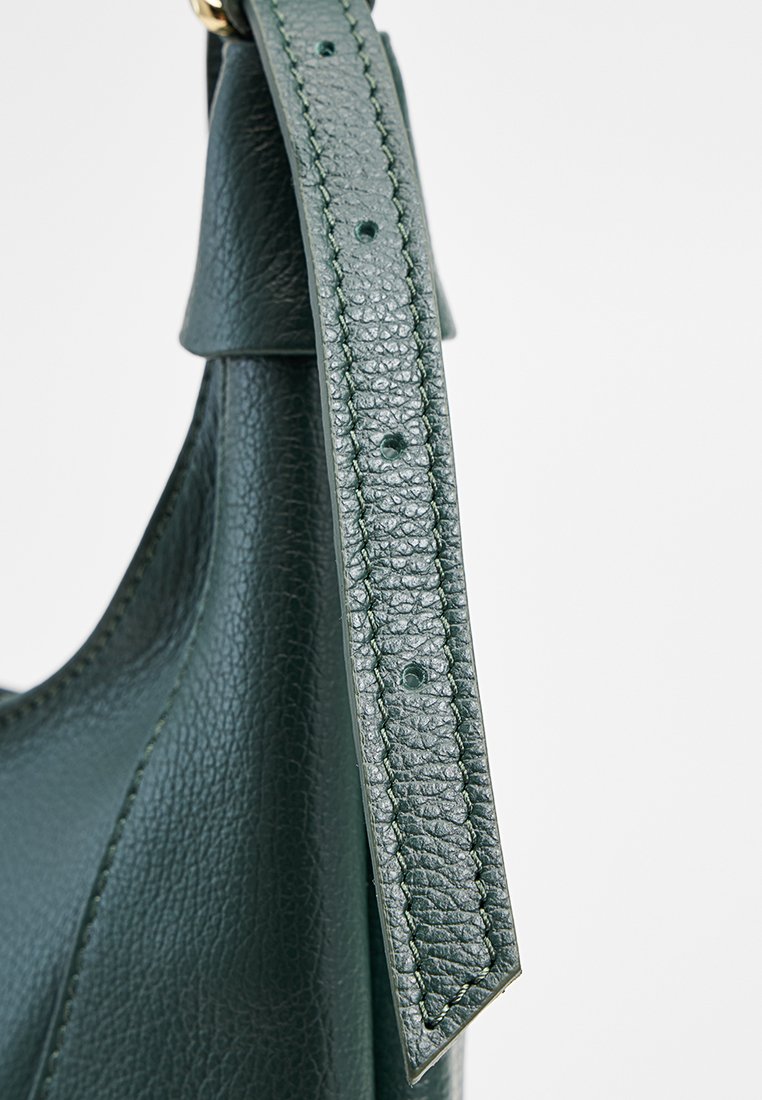 Bolso de mano de cuero verde con acabado texturizado, que presenta una correa larga con costura y pequeños agujeros para ajuste.