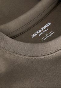 Olivově zelené bavlněné tričko s žebrovaným kulatým výstřihem a bílou značkovou štítkem s textem. Hladký povrch, minimální designové prvky.