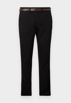 Mustad kehast slim-fit püksid, millele on lisatud tumepruun nahkvöö, stiilitud puhta ja kaasaegse välimuse saavutamiseks ühtlasel heledal taustal.