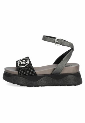 Sandales compensées noires et argentées avec une tige texturée, une bride de cheville ajustable et un accent métallique décoratif. Design de semelle ondulée.