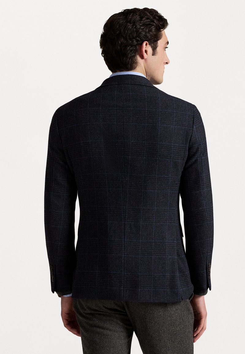 Blazer a quadri blu navy con tessuto testurizzato, rever a punta e due bottoni; presenta una schiena ventilata e dettagli nei polsini; vestibilità su misura.